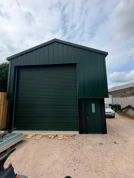 Green steel industrial unit with roller shutter and personnel door