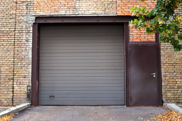 Grey roller garage door on a brick garage with side door
